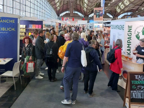 La Male Edizioni Fiera del Libro di Francoferte Monica Macchioni Persone che camminano tra gli stand della Fiera del Libro di Francoforte si vede anche quello di Male Edizione di Monica Macchioni